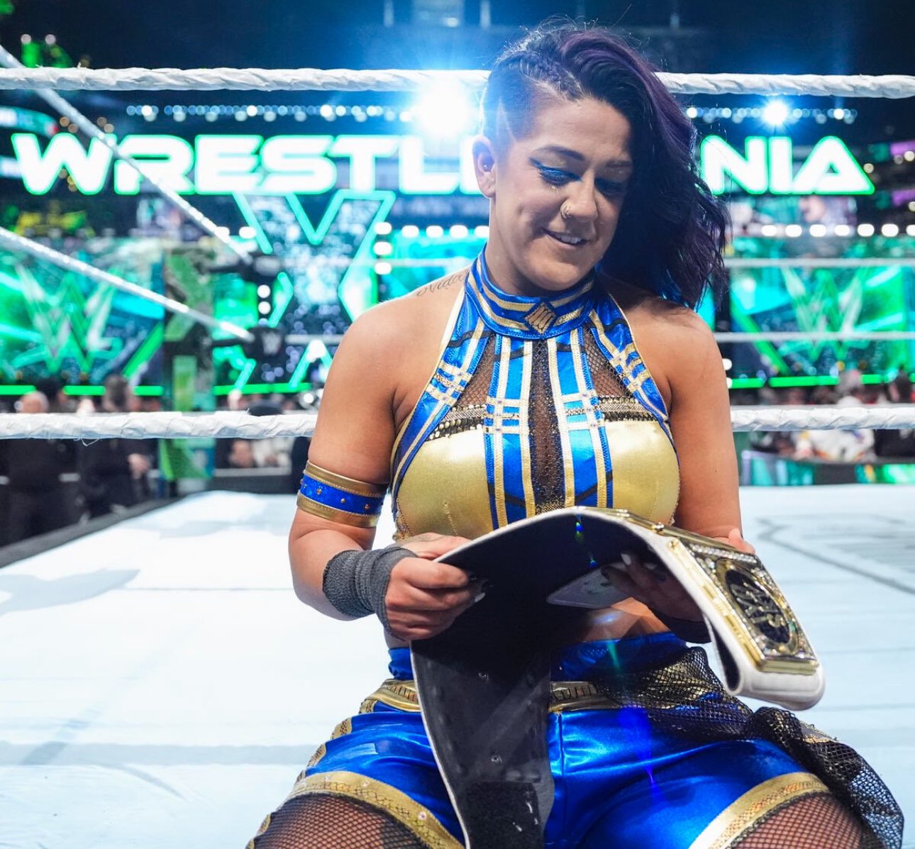 Bayley holding on to her WWE Women's Championship belt, with the light of WrestleMania shining on her from behind.